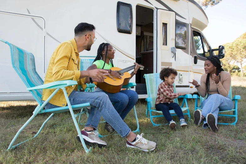 the family is sitting outside playing a guitar