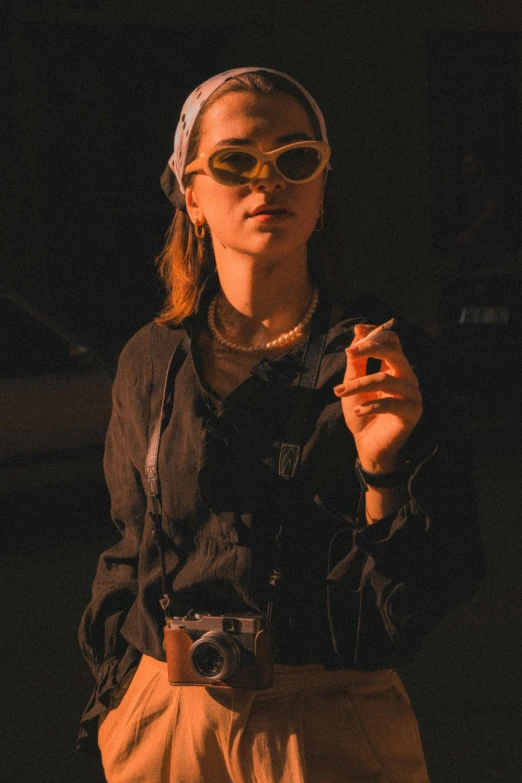 woman in dark outfit holding cigarette and looking at camera