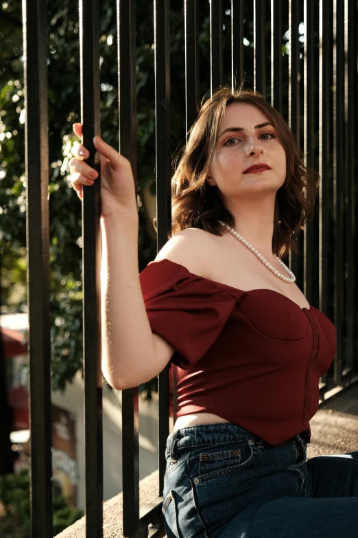 a woman is sitting against a gate smoking