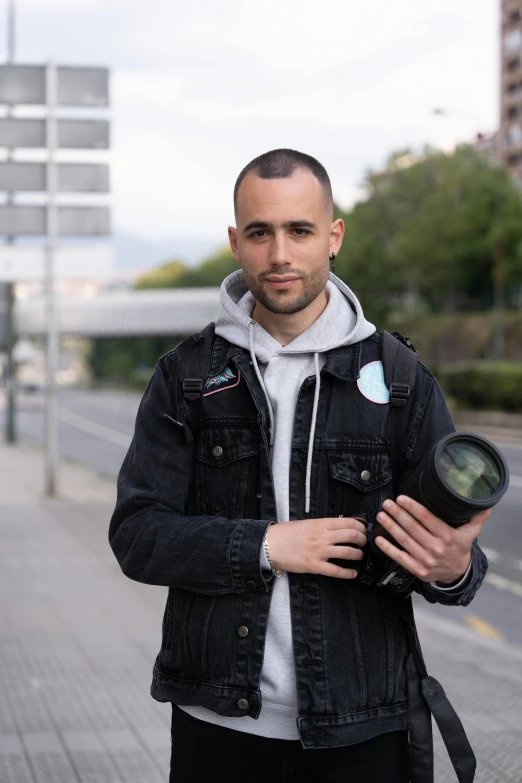 a man standing on a city sidewalk with a backpack holding an object