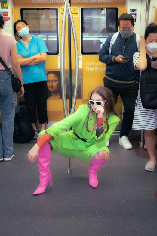 girl in green outfit on subway with face mask and leg ces