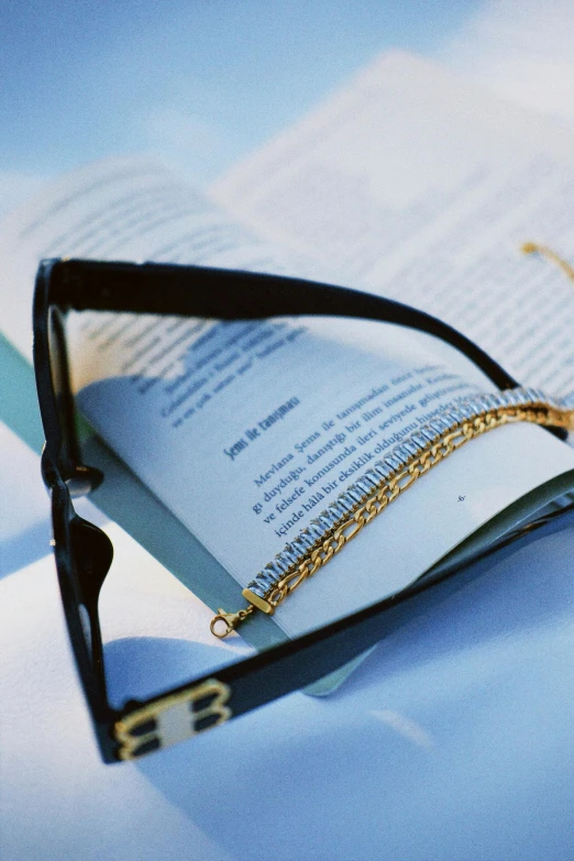 an open book sitting next to eyeglasses and a pen