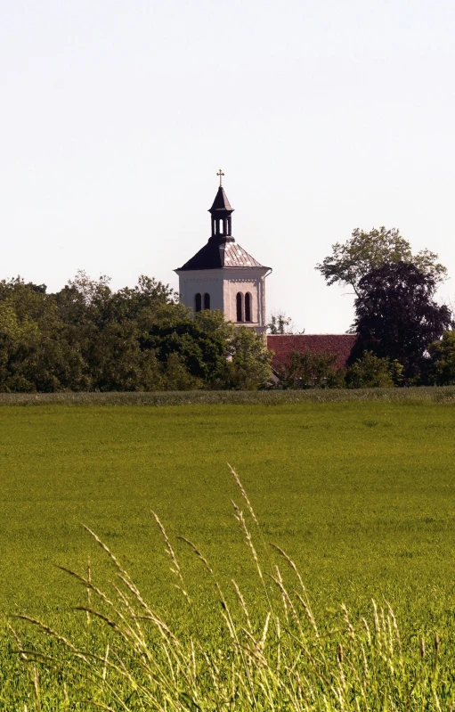 a large grassy field with a tall white building behind it