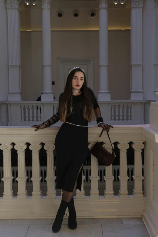 a woman wearing a skirt and black sweater posing on a balcony