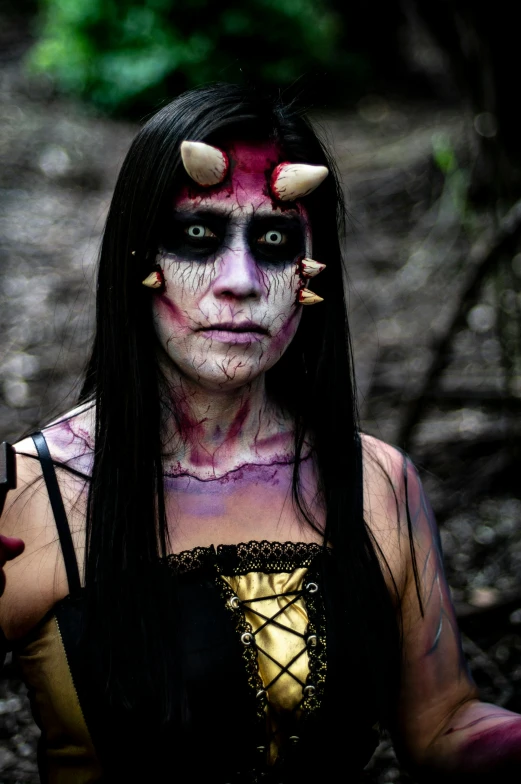 a woman in white makeup, long hair and horns with evil makeup