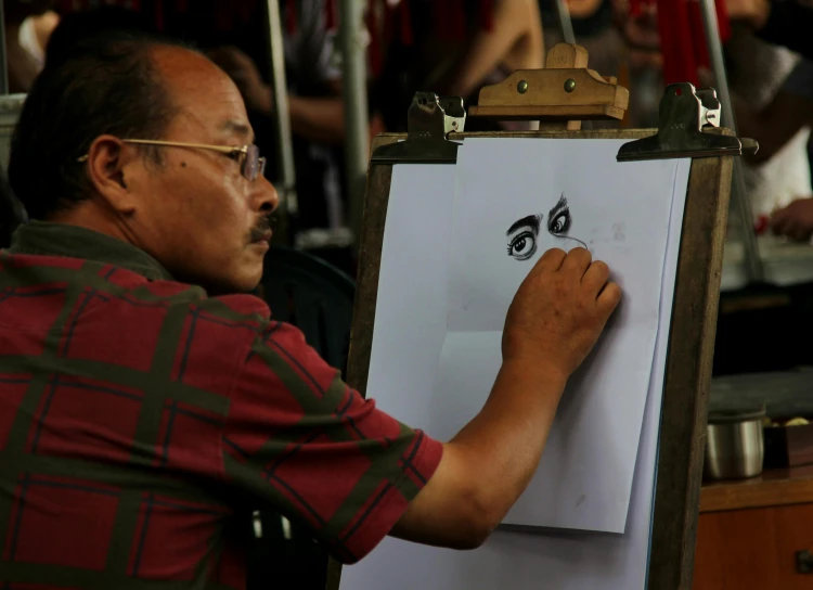 a man drawing eyes on a white paper