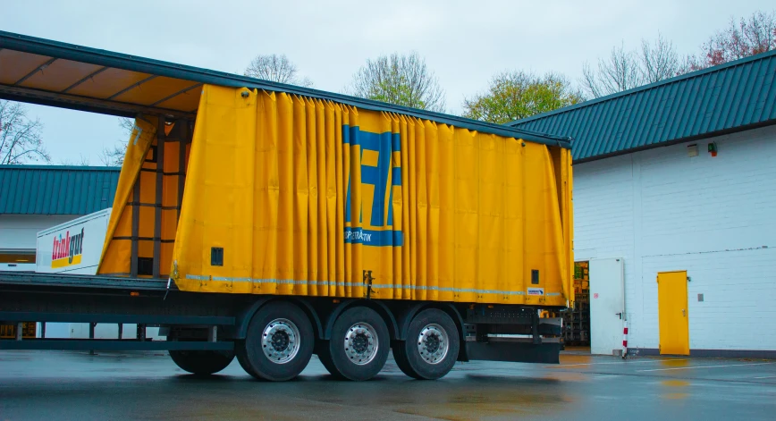 a large yellow box truck parked on a cement lot