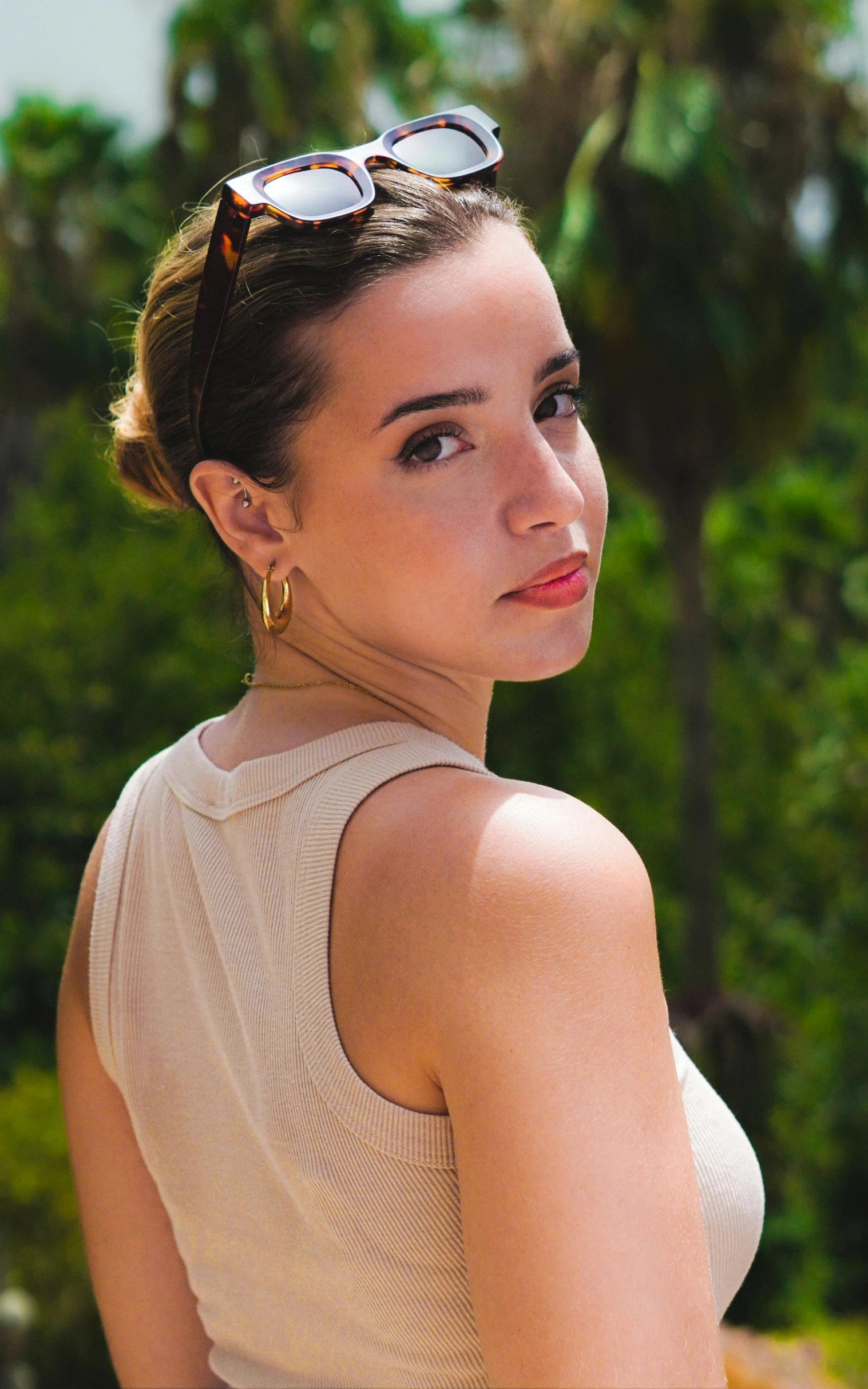 a woman in white top and sunglasses looking off into the distance