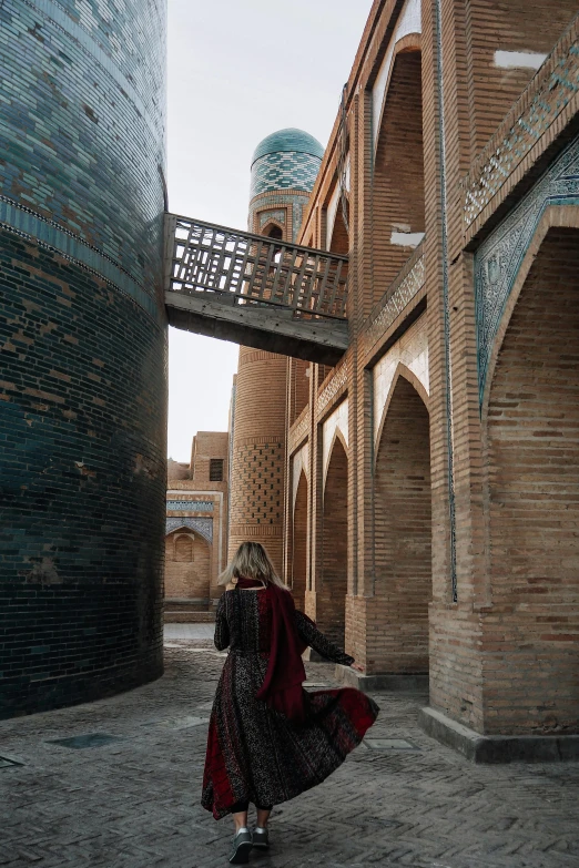 a woman is walking in a courtyard, near arches