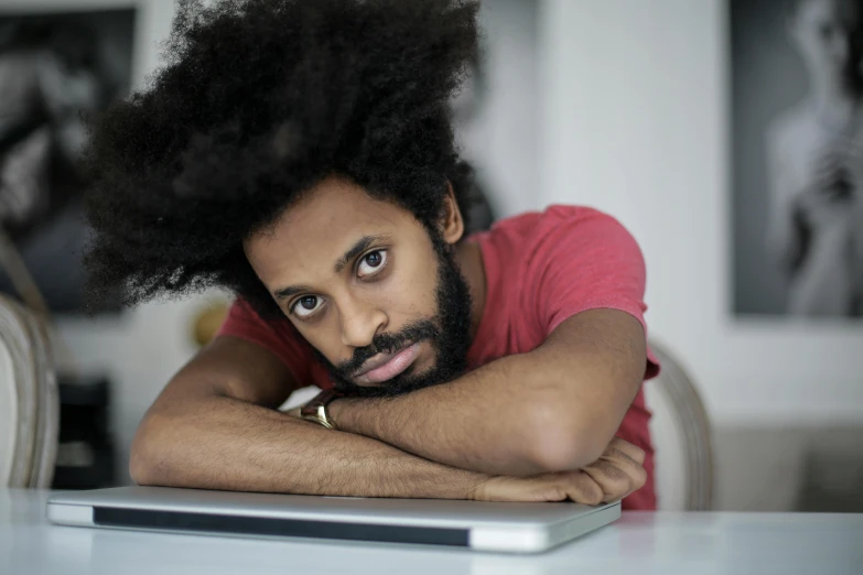 a man with a beard with his arms resting on his lap top