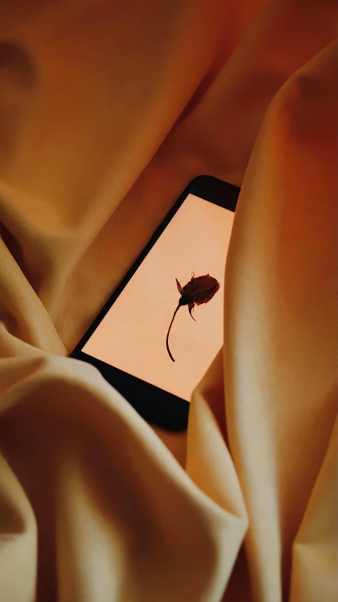 the phone is sitting on the cloth near a leaf