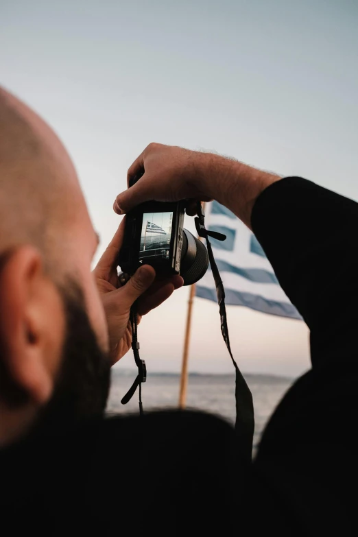 a man holding up a camera near the ocean