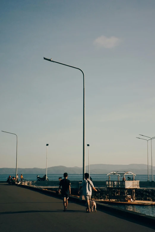 two people walking on the edge of a walkway over a lake