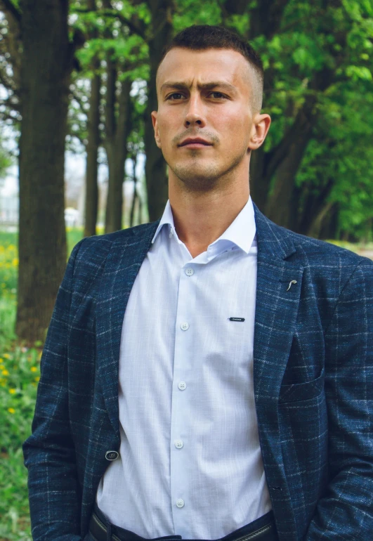 a man in a blue suit standing outside in the forest