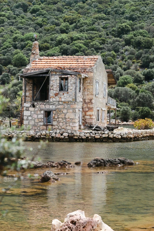 a old stone cottage on the shore of a lake