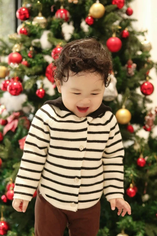 small child standing in front of a christmas tree