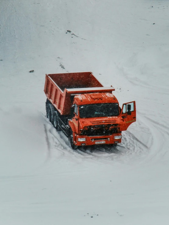 a red dump truck in the snow on the ground