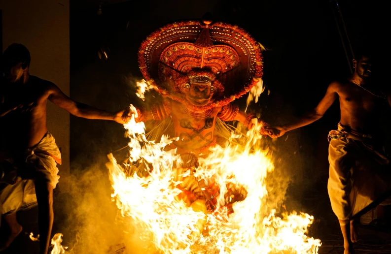 three men in front of a fire with a human face on it