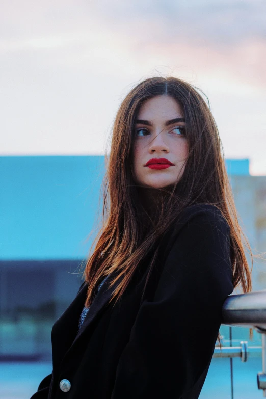 a woman is standing in front of a balcony near water