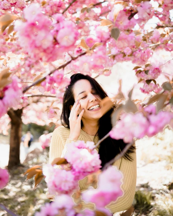 woman smiling at camera surrounded by pink flowers