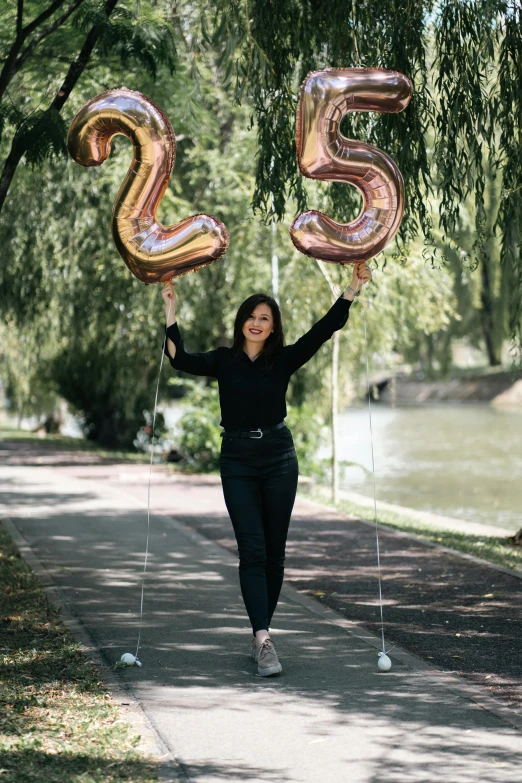 a woman on a path carrying two huge balloons