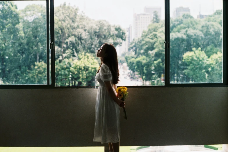 girl standing against window looking out at park