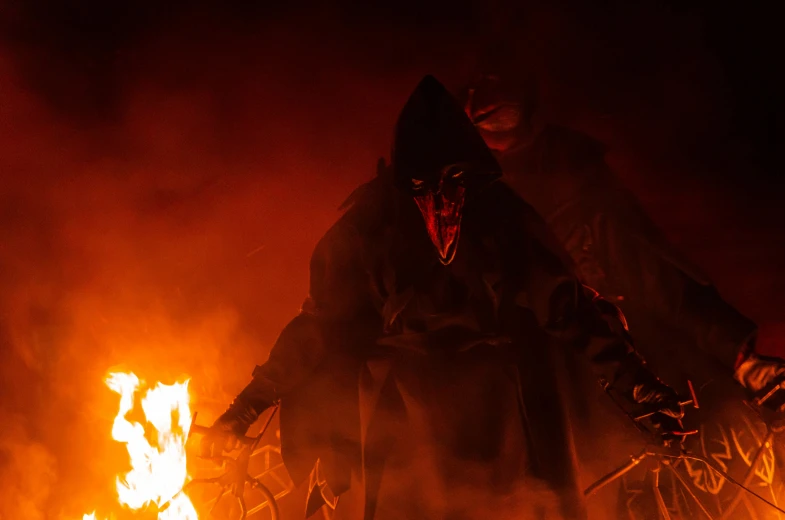 a man standing next to fire wearing a mask