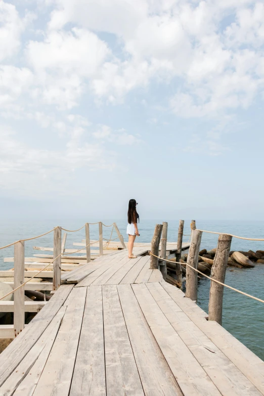 a woman walking on a wooden dock by the water