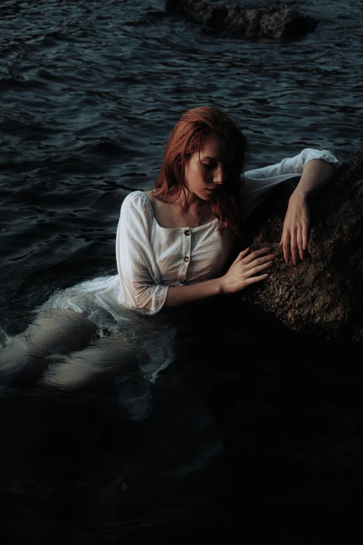 a woman wearing a white top laying in a lake