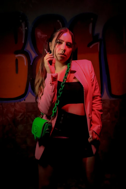 a woman in pink jacket standing with cellphone near wall