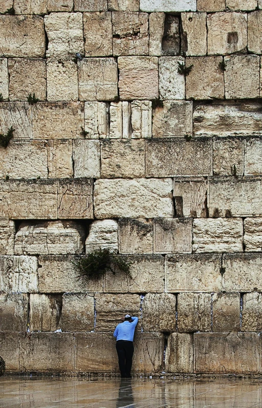 a person standing at the base of a tall stone wall