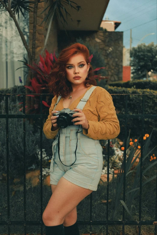 the woman in a denim dress is holding a camera