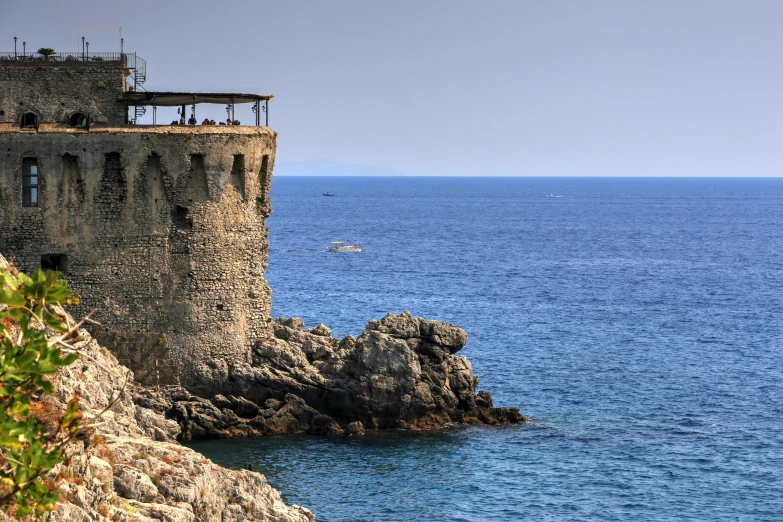 two buildings built on a rock outcropping by the ocean