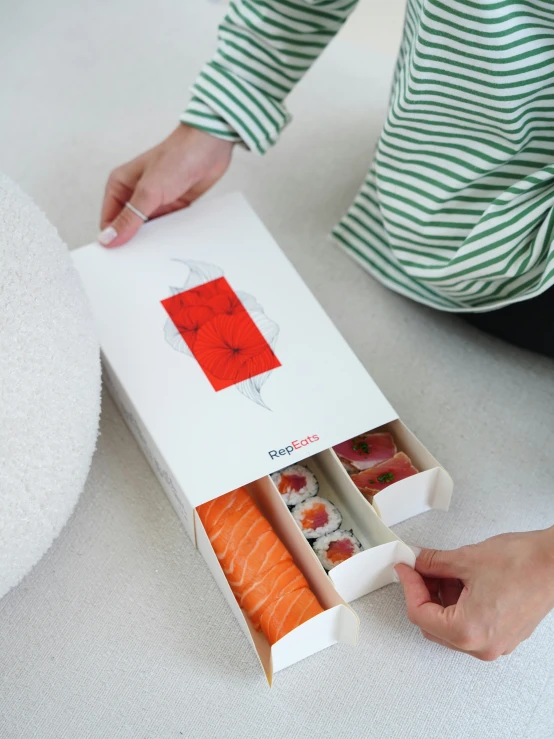 a woman holding a sushi box full of salmon