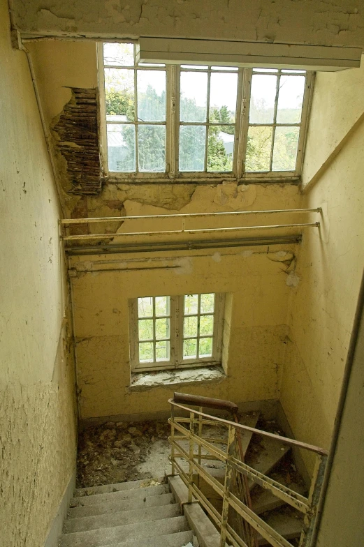 the stairway leading up to an open window in a run down building