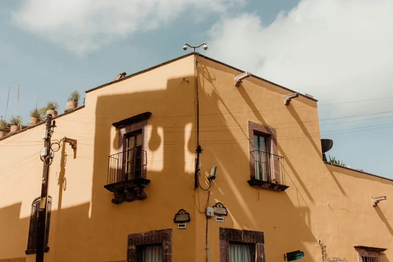 several windows on a yellow building with a red tiled roof