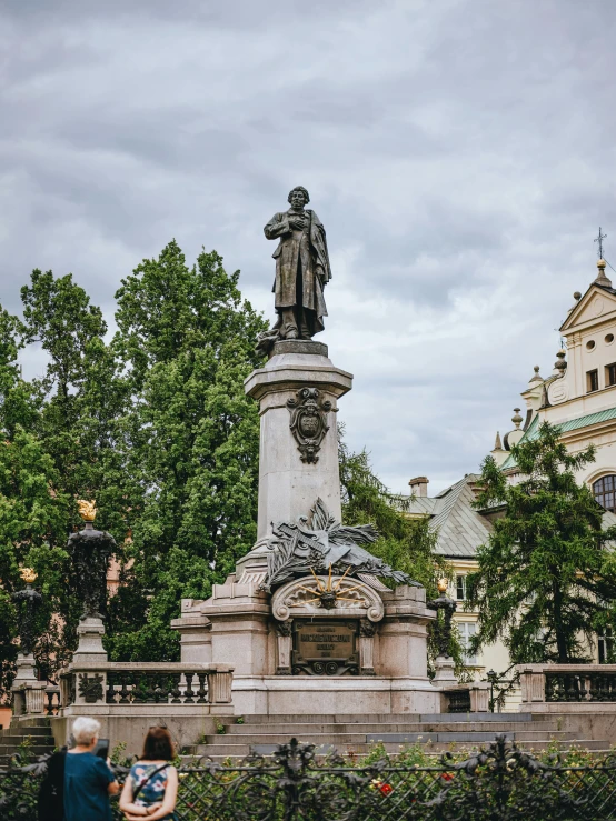 an older couple standing around a fountain looking at the monument