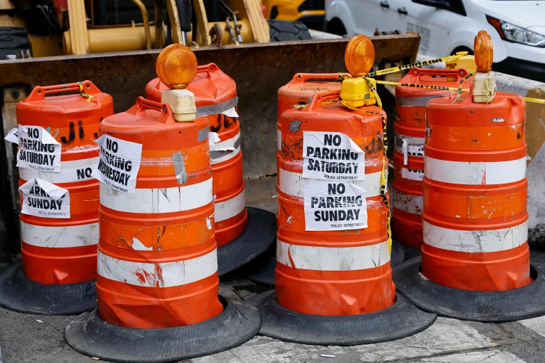 a group of orange street signs sitting on top of a sidewalk