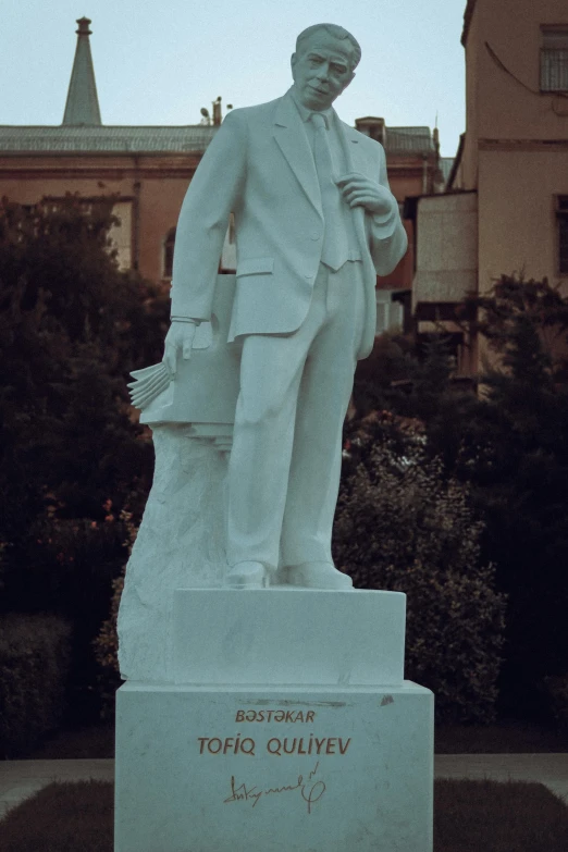 a statue in a yard with trees and a building behind it