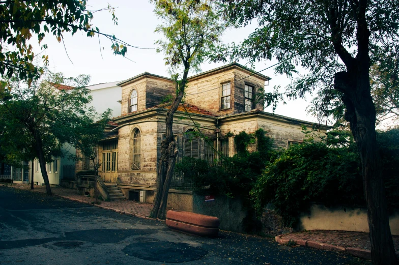 a large old house sitting in a tree filled sidewalk