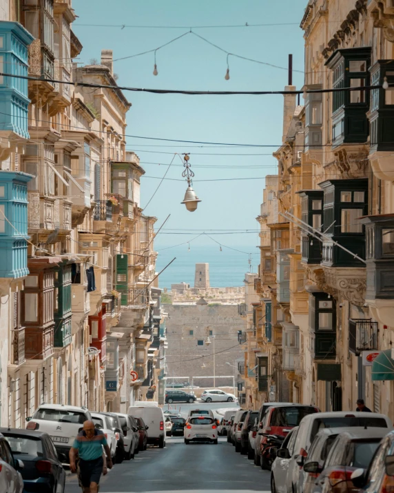 a person is walking down a street with many parked cars and vehicles