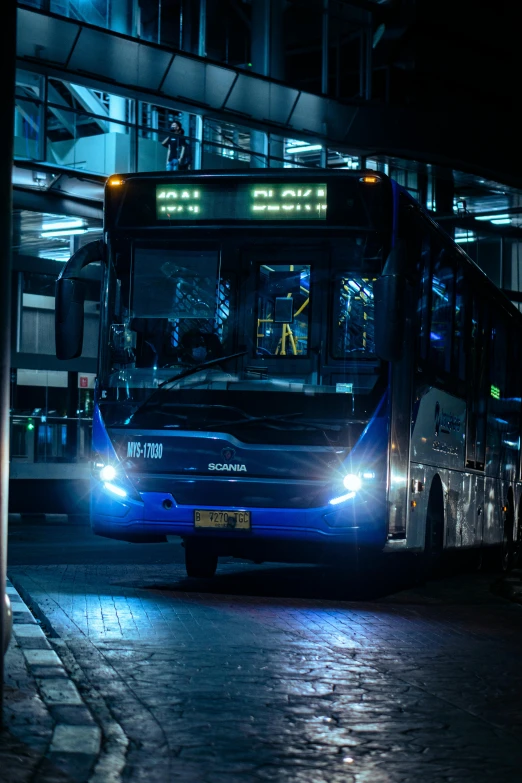 a blue bus traveling down a dark street at night