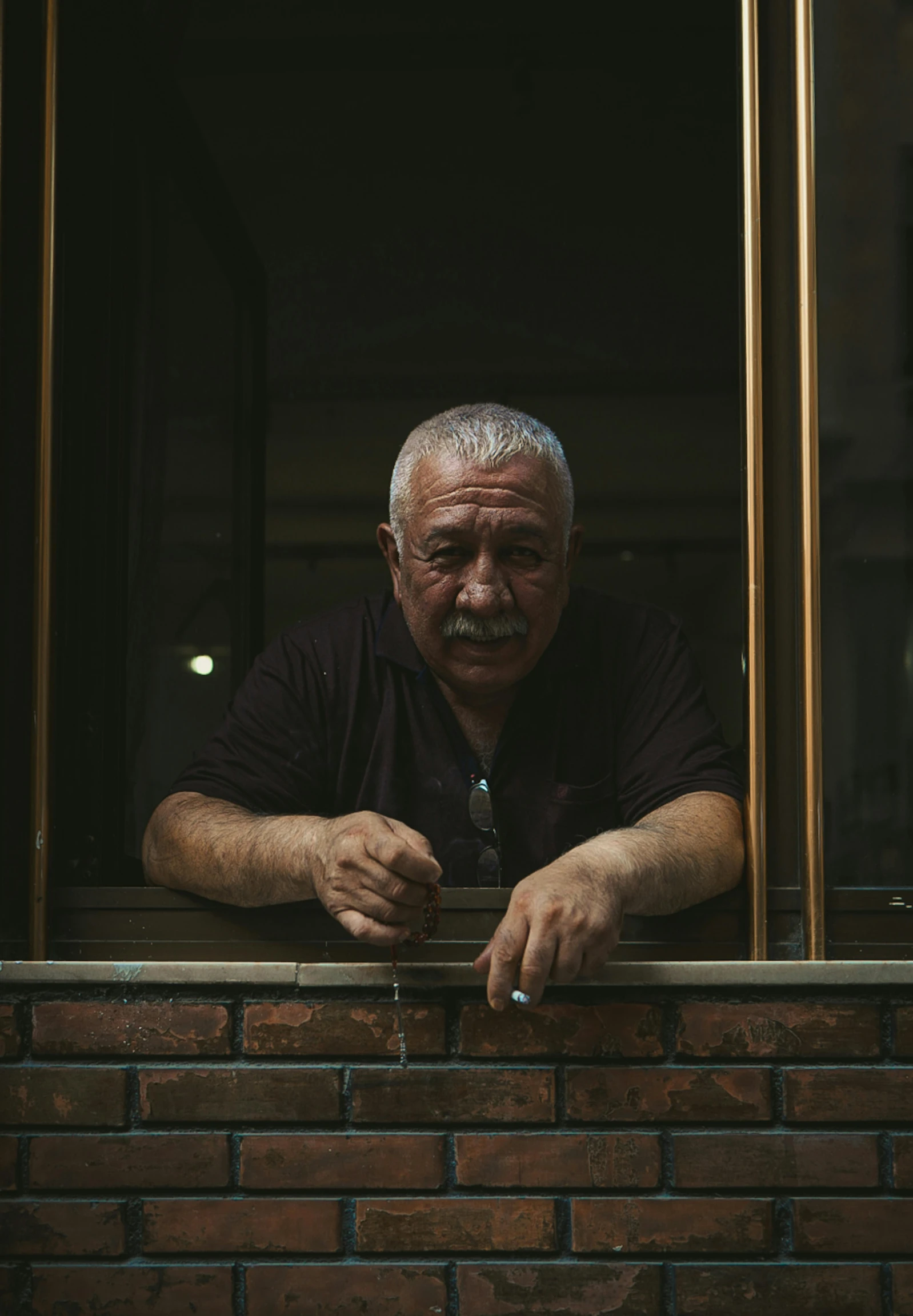 an older man leans on a window ledge