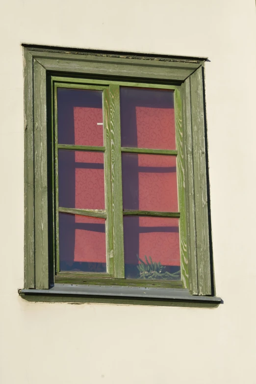 the window on the side of the building has green frames