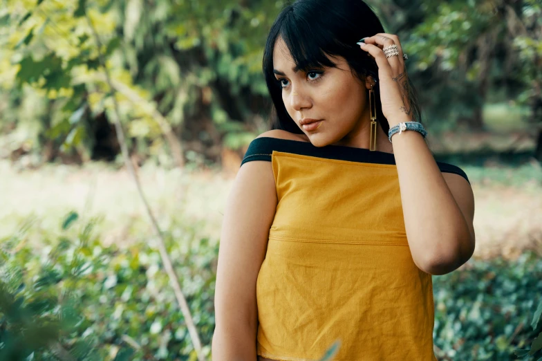 a woman in a yellow top standing in front of plants