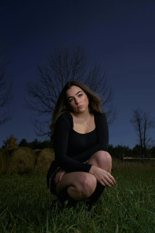 a beautiful young woman sitting on top of green grass