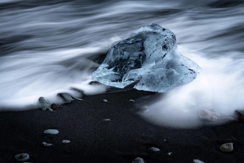 an iceberg on a rocky beach near the water