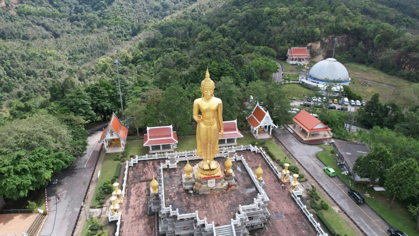 a big golden statue is placed next to a mountain