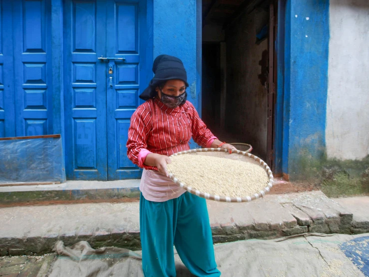 a young woman carries grains through her home