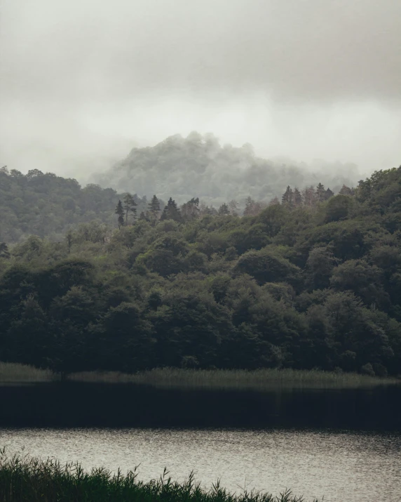 a lake is shown in the foreground as it shrouds with fog